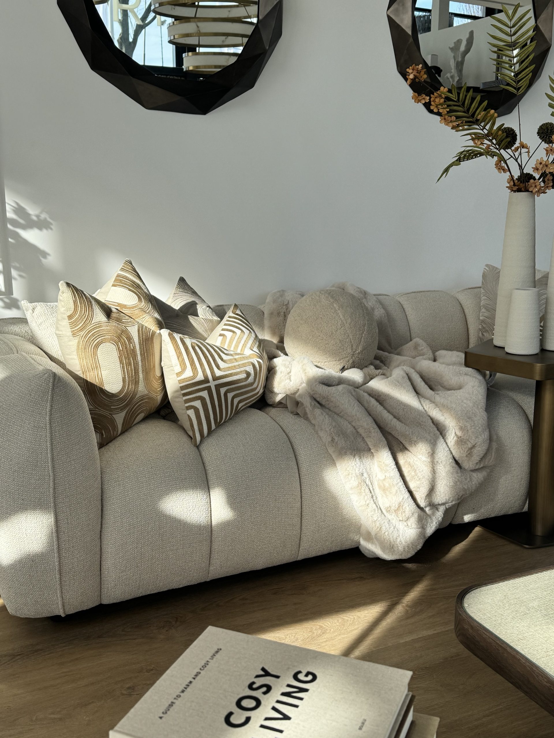 Beige bank met gedessineerde en effen sierkussens en een bontplaid die losjes over de zitting valt